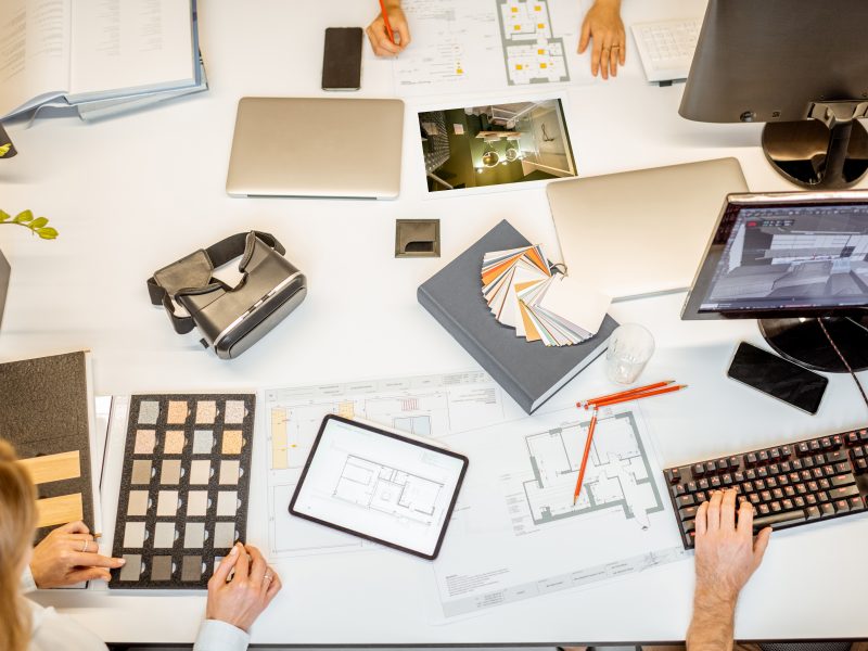 Creative workplace of designers or architects, designing interior. Top view on the table with various architectural drawings, computers and office supplies