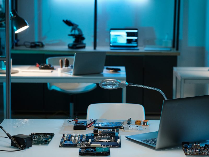 Workplace of repairman or technician with laptop, magnifying-glass, repairing equipment and hardware on desk in laboratory
